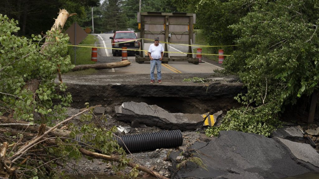 A motorist stops to survey the damage to a washed-out bridge