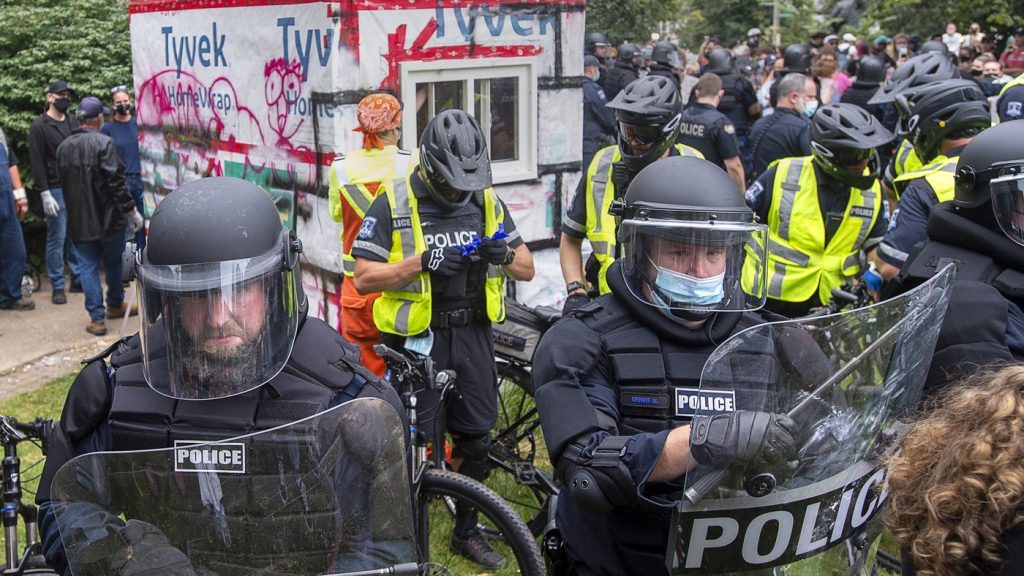 Police attend a protest after the city removed tents and small shelters for homeless people in Halifax on Wednesday, Aug. 18, 2021.