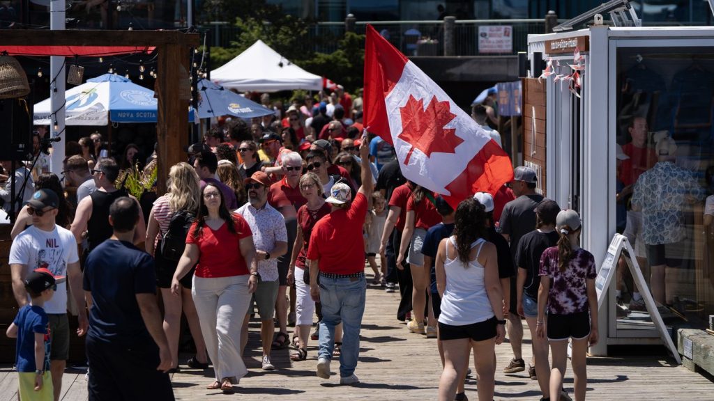 A reveller carries a Canada flag through a crowd on the Halifax Waterfront during Canada Day celebrations in Halifax, on Tuesday, July 1, 2025. THE CANADIAN PRESS/Darren Calabrese